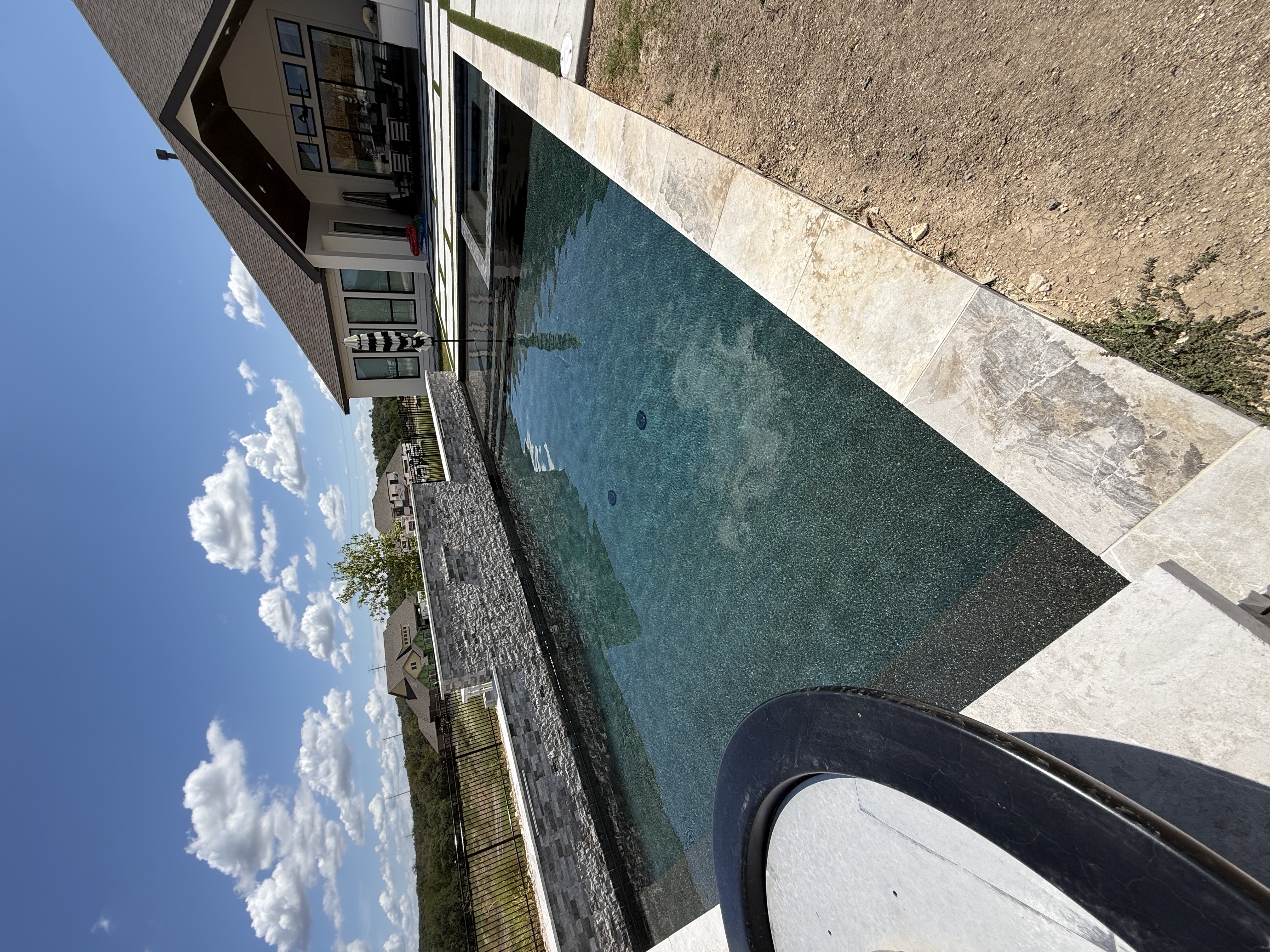 Boerne pool with three sheer descent waterfalls on a grey stacked-stone wall, integrated square spa and geometric floating pavers with turf strips