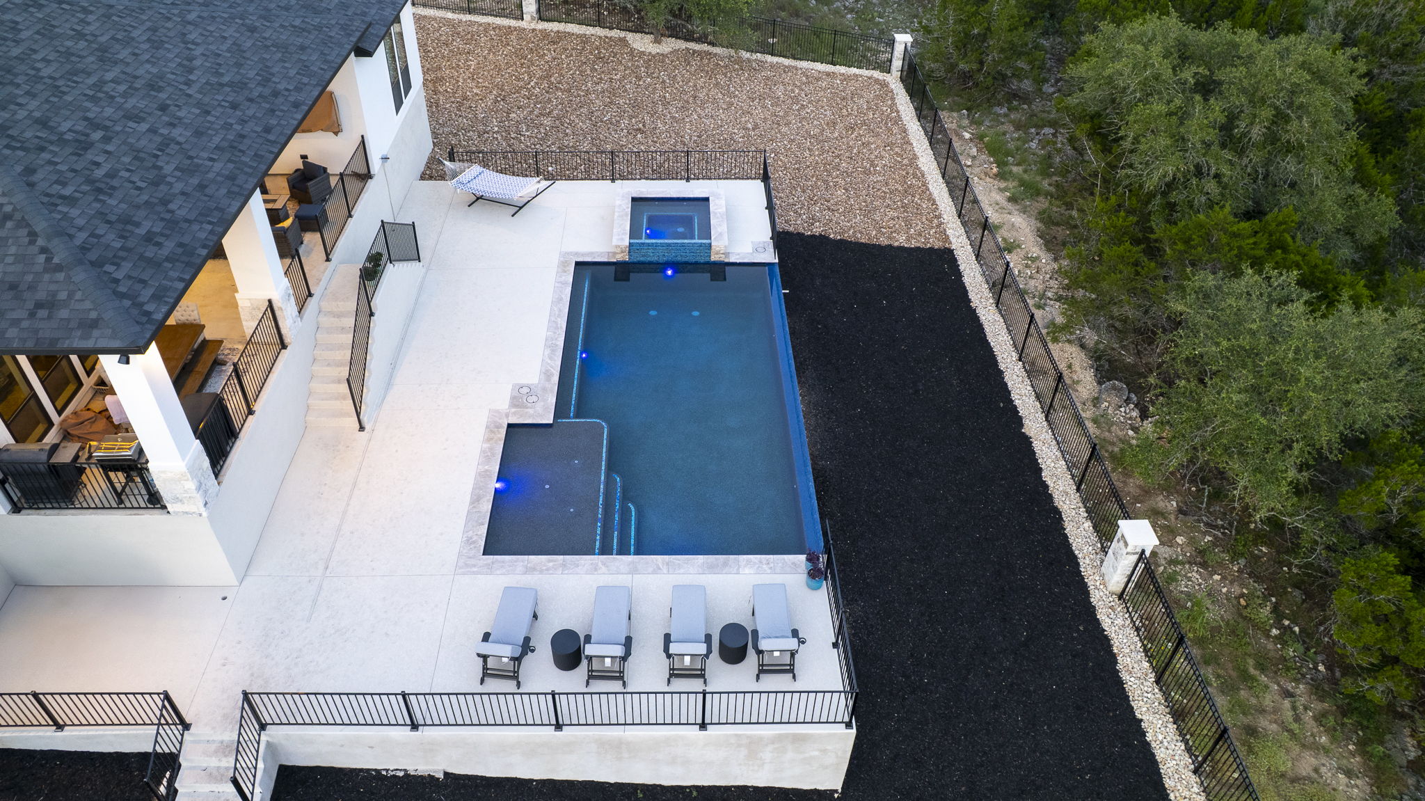 Aerial view of a New Braunfels pool with tanning ledge, raised square spa and covered patio dining area