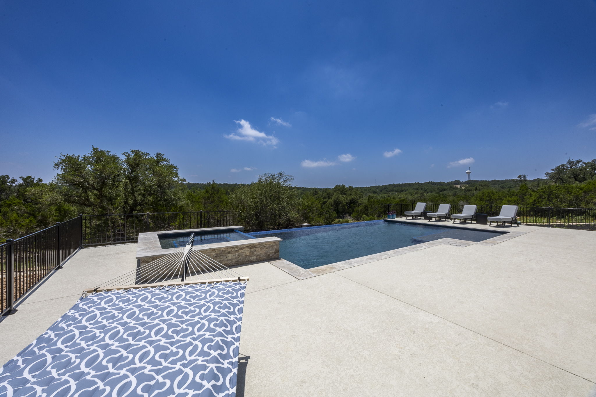 New Braunfels elevated pool patio with a raised stone-clad spa overlooking Hill Country views