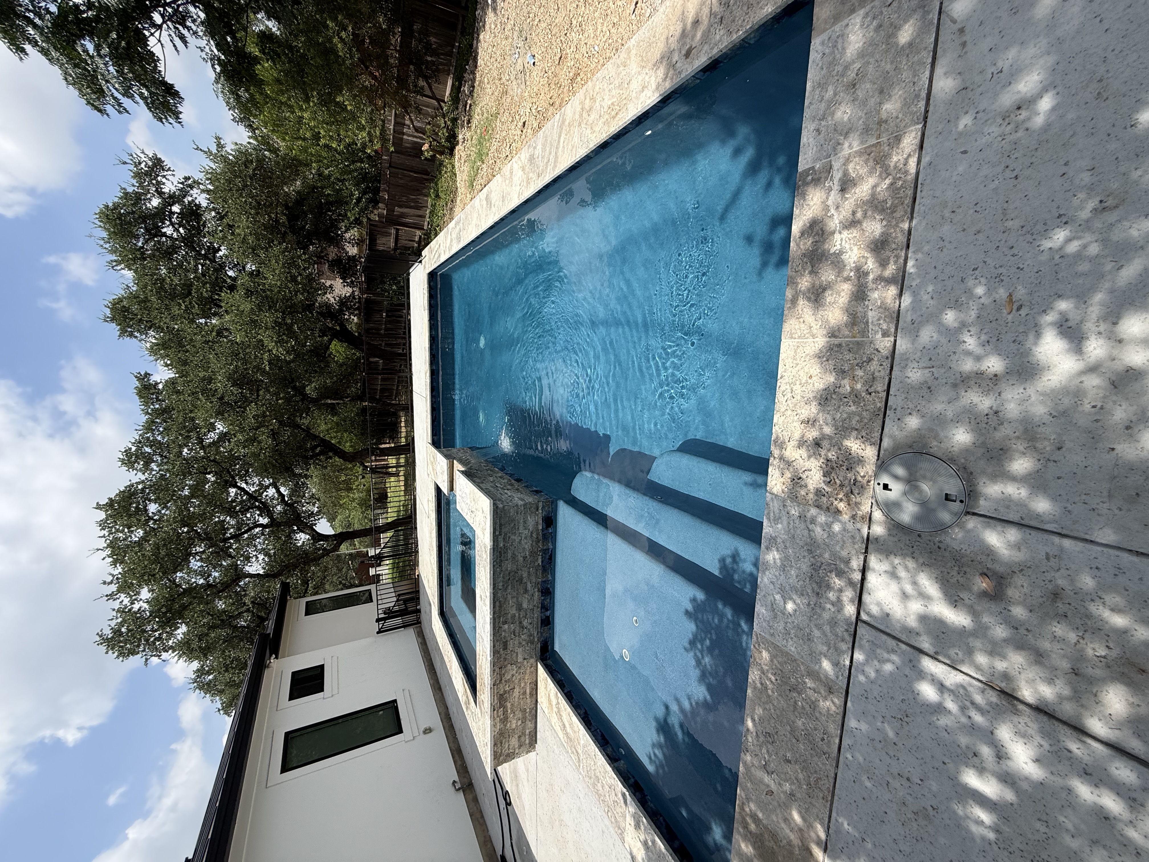 San Antonio pool with a raised square spa, stone coping and paver patio shaded by mature trees